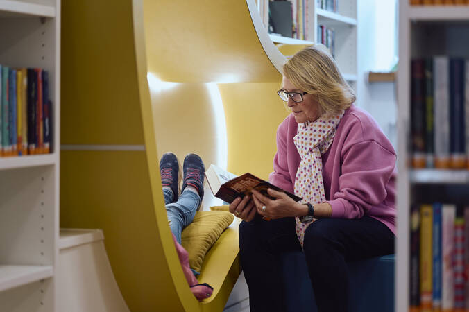 Frau Constanze Amort liest einem Kind, das in einer gelben Leseecke in der Kinder- und Jugendbibliothek Hüfingen sitzt, ein Buch vor.