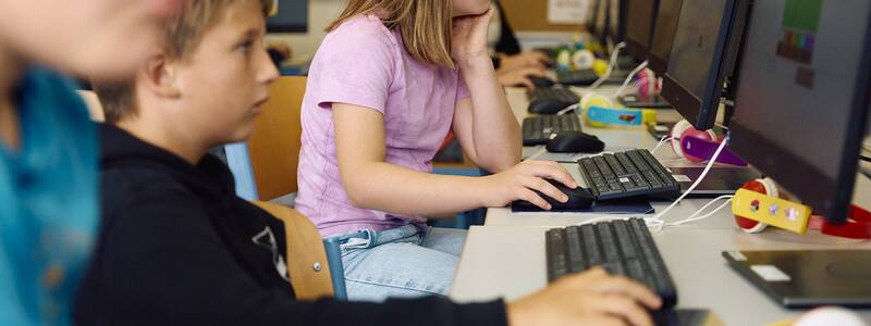 Mehrere Kinder arbeiten konzentriert an Computern in einem Klassenraum der Schellenberger Schule.