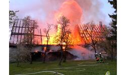 Zwei Feuerwehrmitglieder löschen ein brennendes Gebäude.