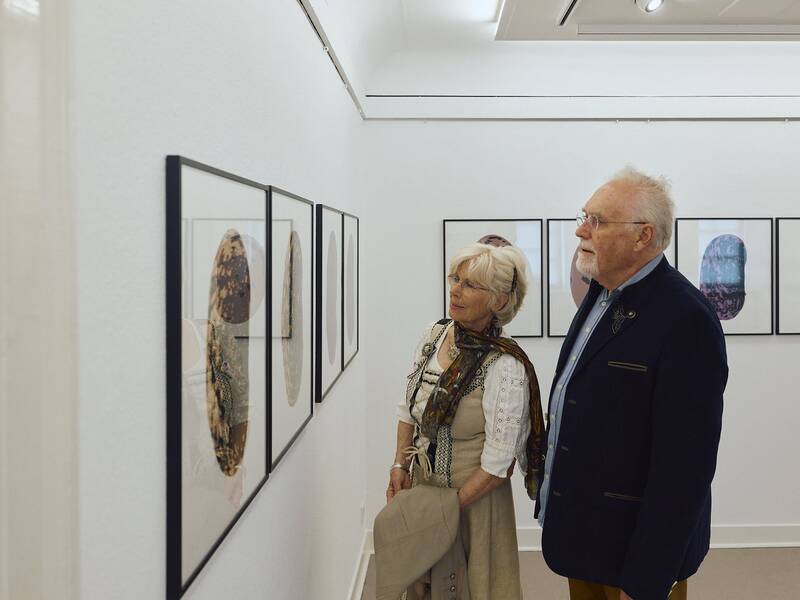 Besucher in traditioneller Kleidung betrachtet Kunstwerke, die an den Wänden des Stadtmuseums ausgestellt sind.