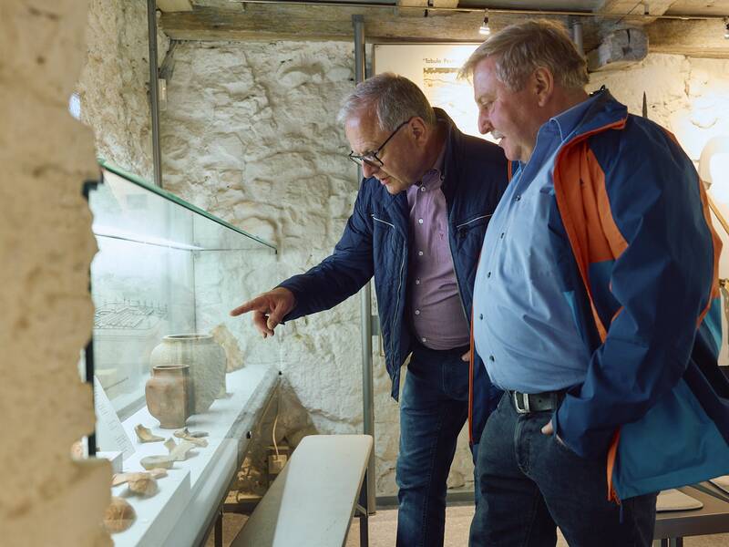 Zwei Männer betrachten aufmerksam Exponate in einer Glasvitrine im Erdgeschoss des Stadtmuseums.