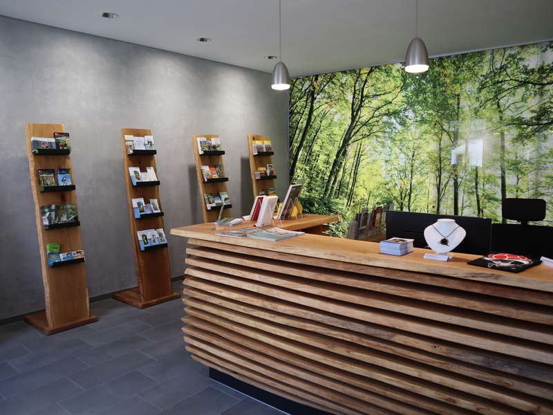Büro mit Theke aus Holz im Hintergrund sind Prospektauslage zu sehen 