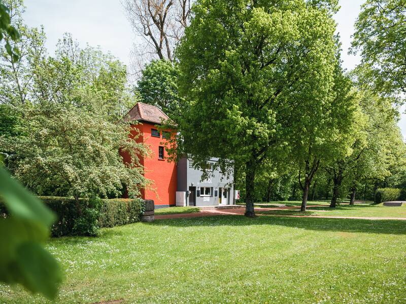Wiese, im Hintergrund ein roter Turm - Kiosk 